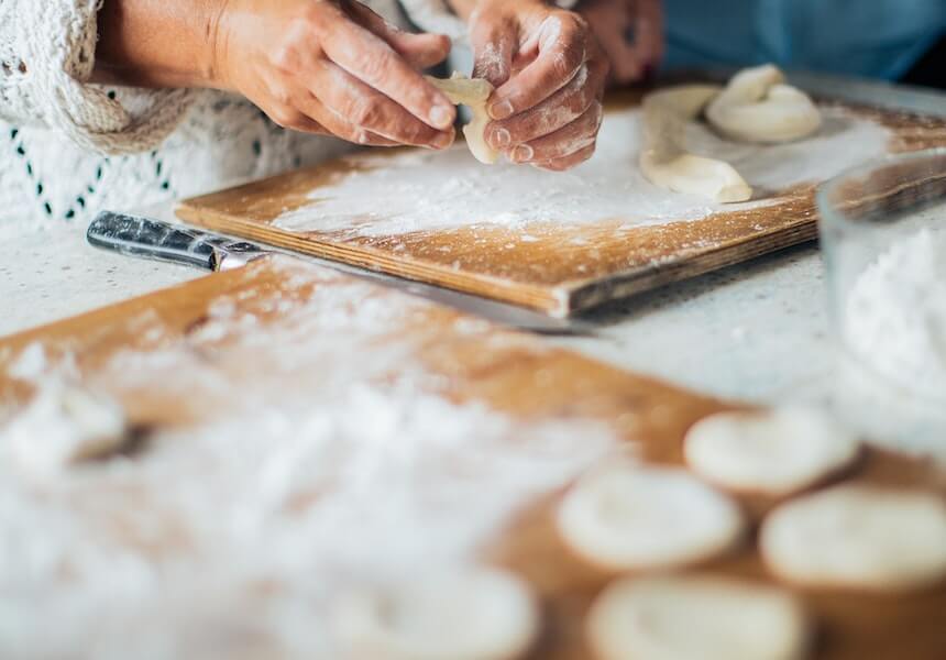 person holding white dough on brown table